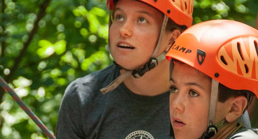 Two people wearing orange helmets hold expressions of concentration 